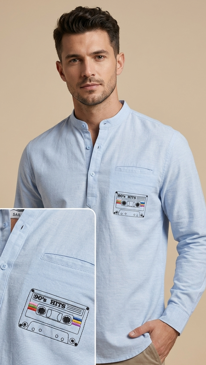 A man wearing a light blue long-sleeve button-up shirt with a chest pocket featuring a 1990s cassette tape graphic. An inset detail box on the left shows a close-up of the cassette pocket embroidery.